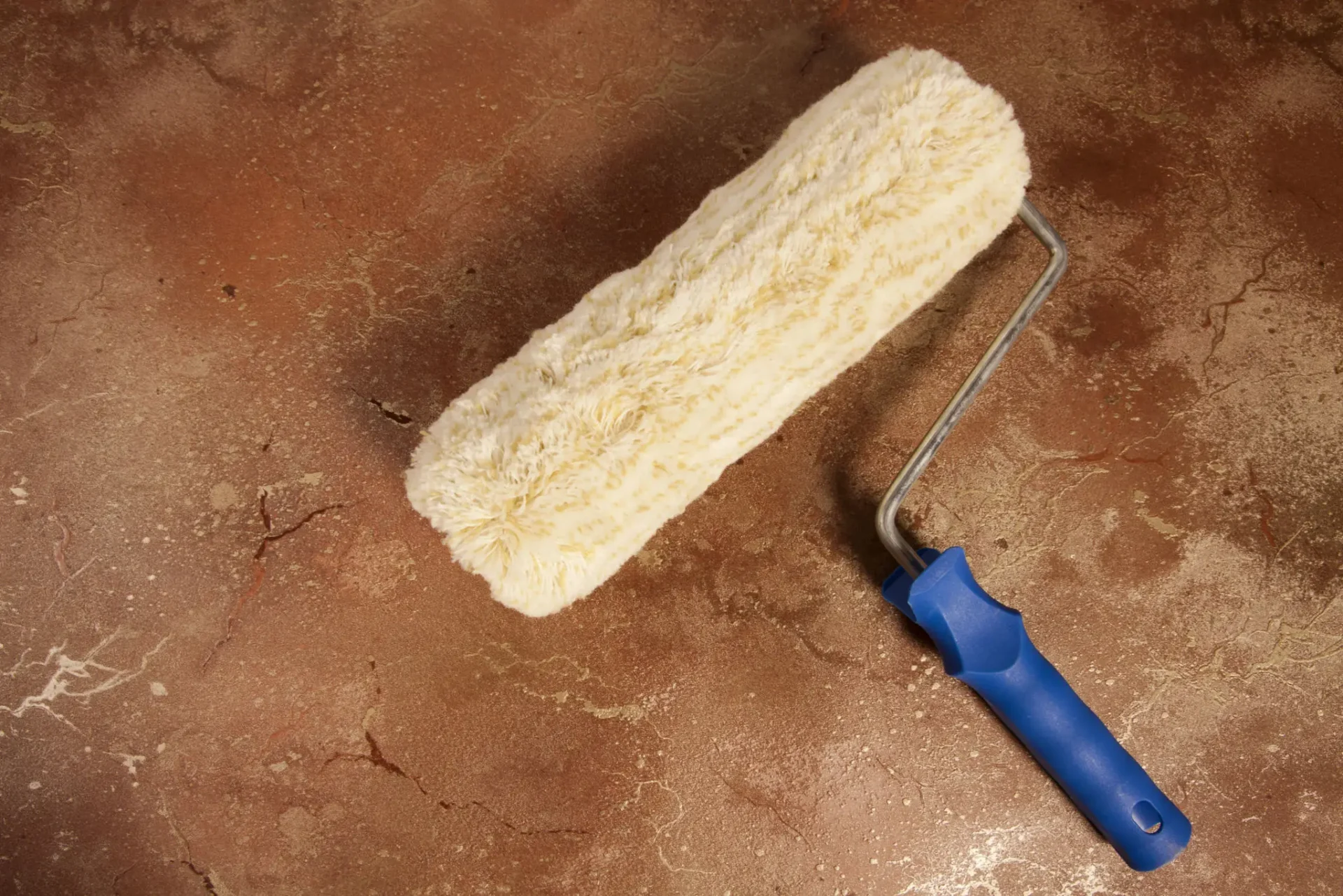 Paint roller on a textured brown surface.