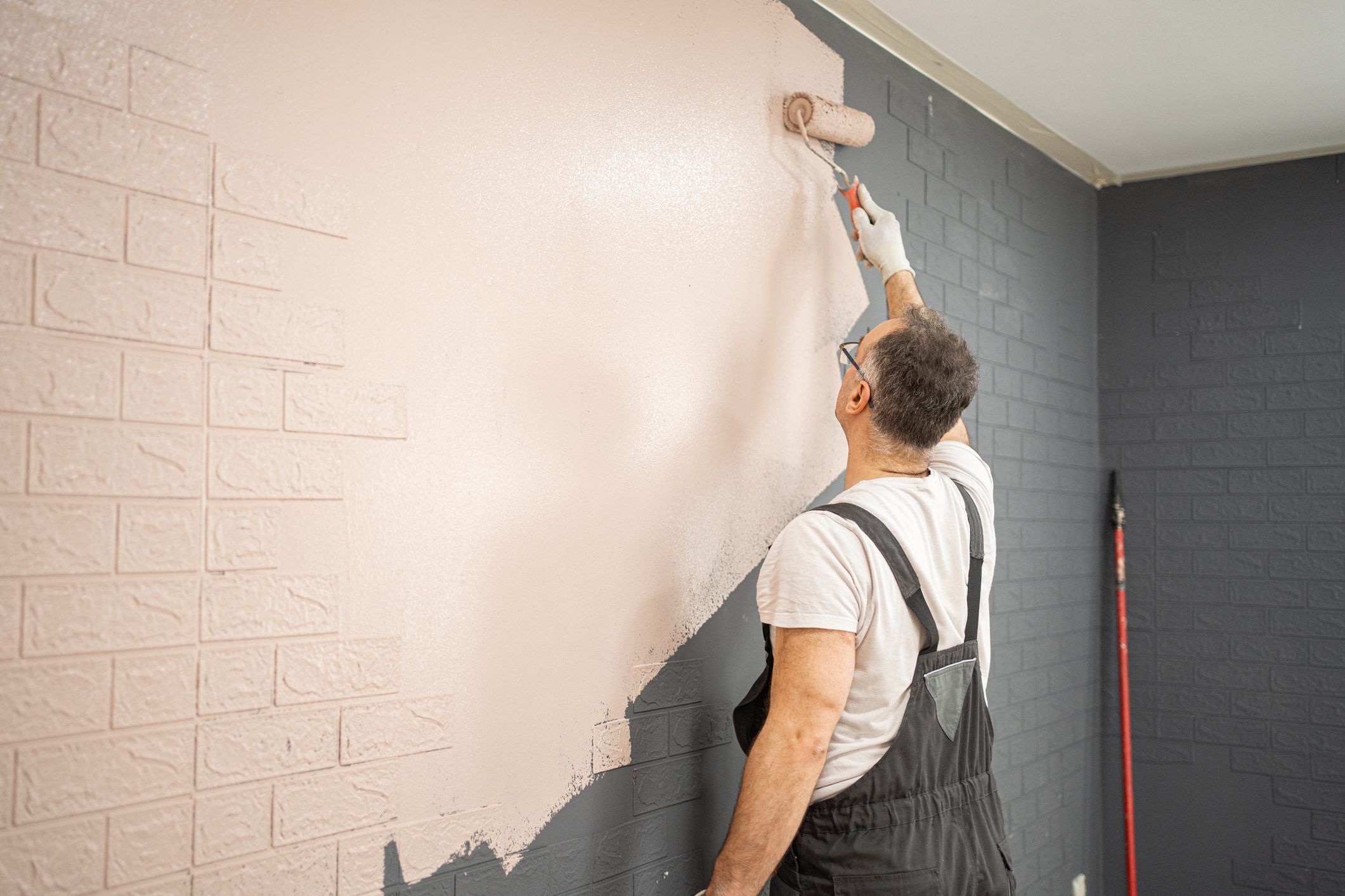 Man painting wall with roller brush.