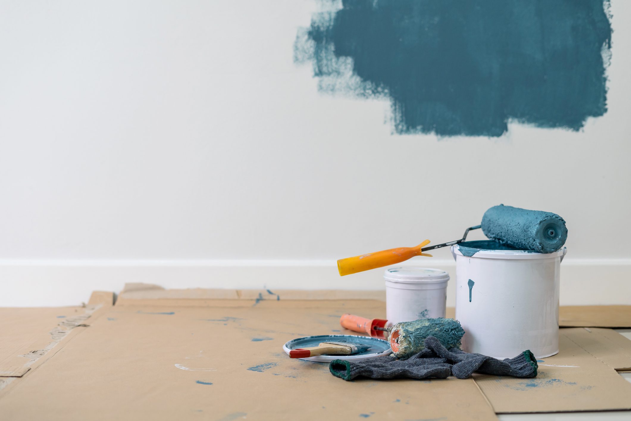 Painting supplies with blue paint on wall.