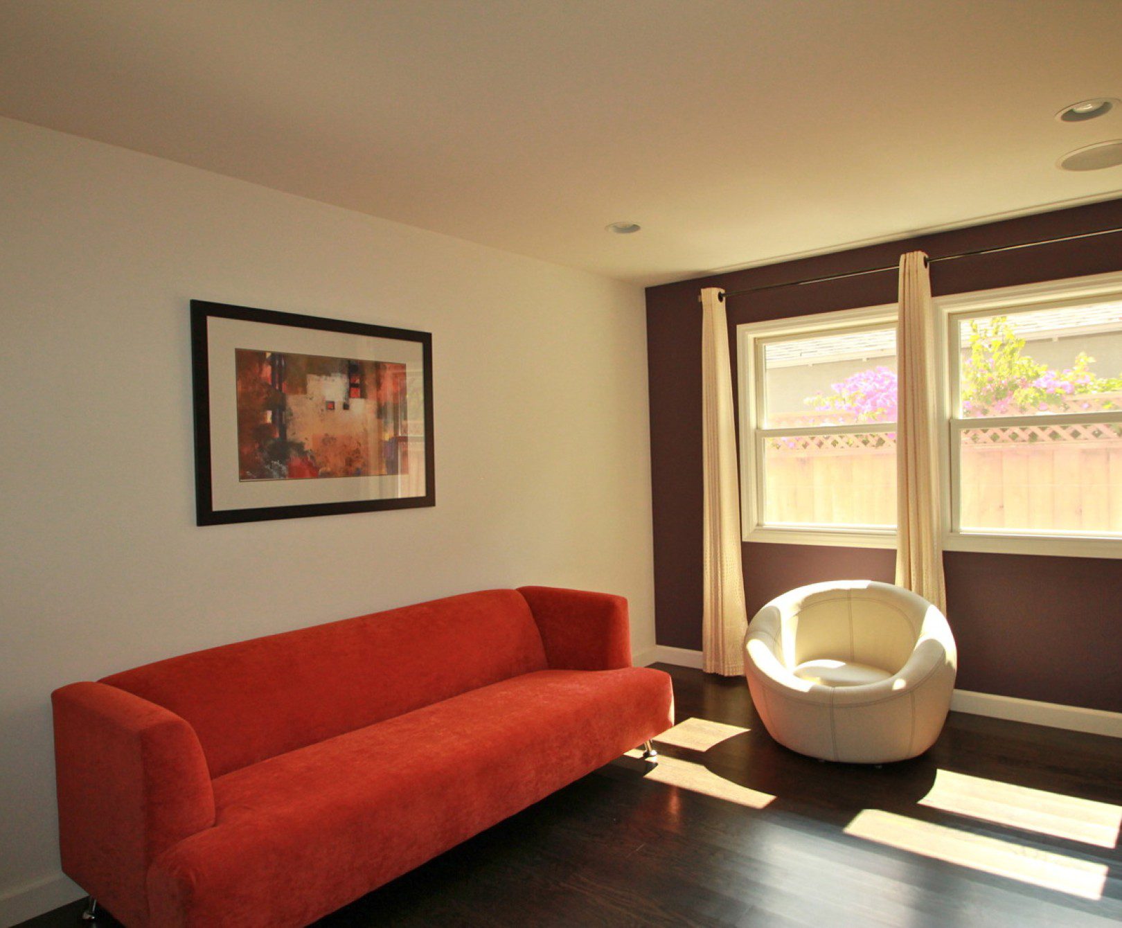 Minimalist living room with orange sofa, chair.