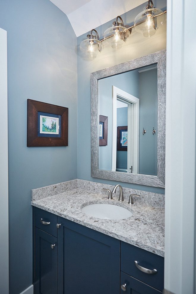 Blue bathroom with mirror and artwork.
