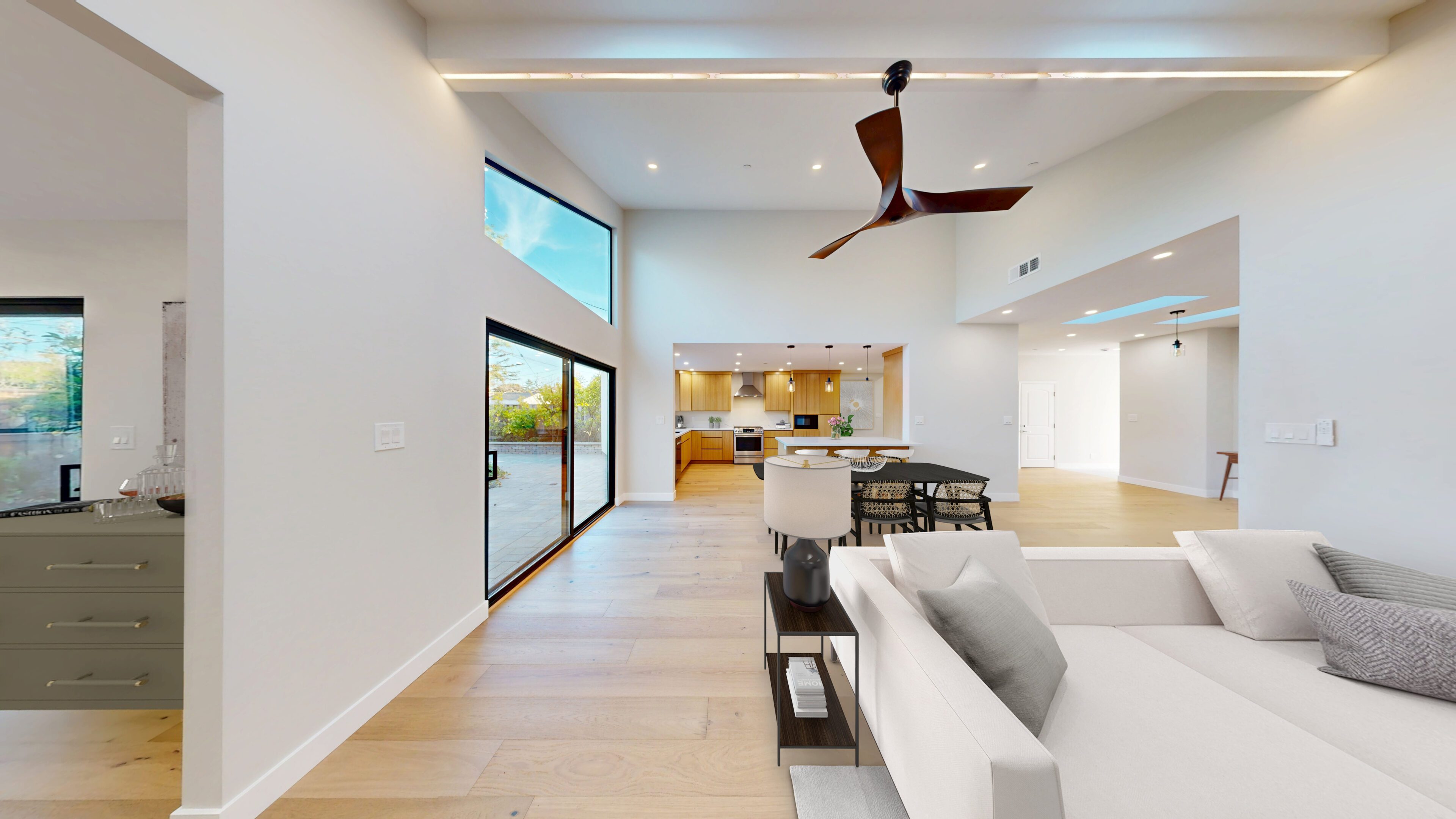 Modern open living room with large windows and ceiling fans.