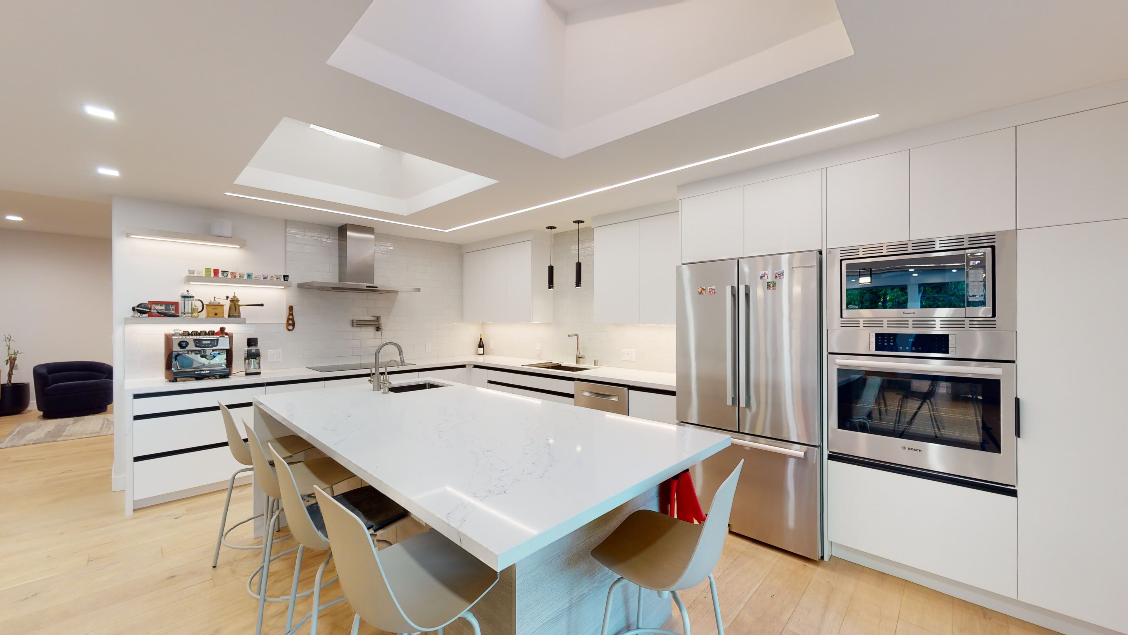 Modern kitchen with a large white island and colorful chairs.