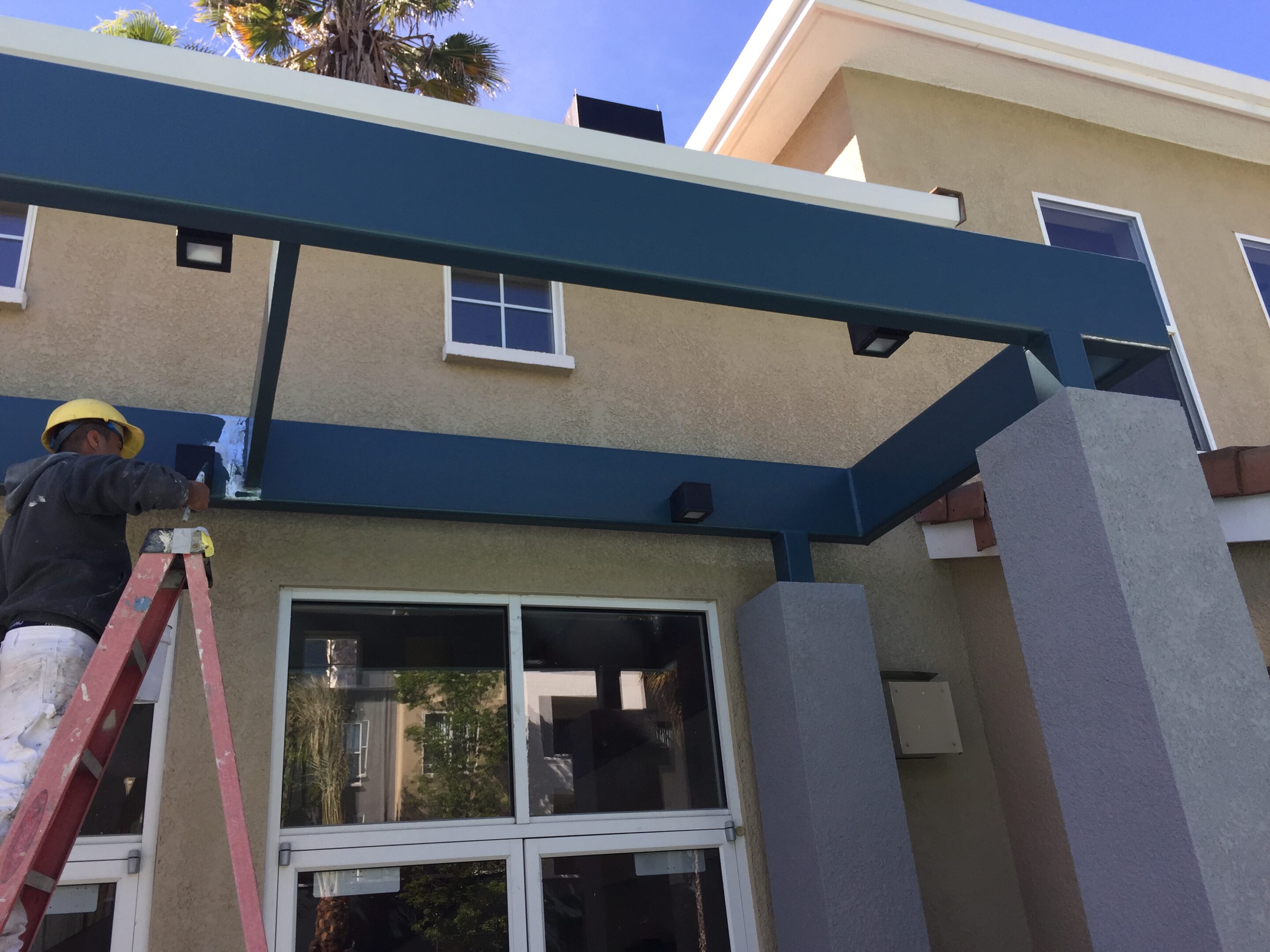 Modern building entrance with glass canopy and beige walls.