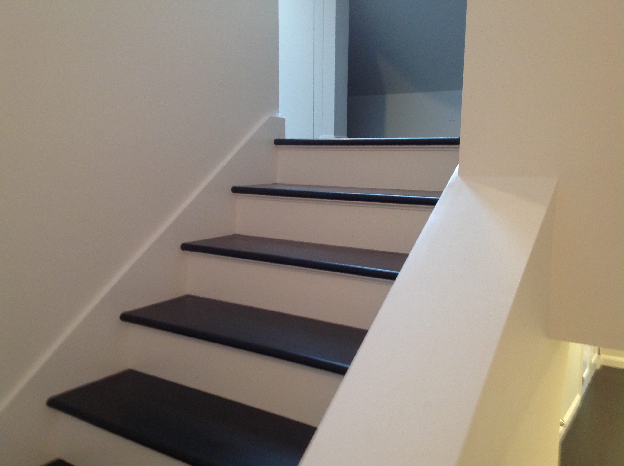 Modern staircase with dark wooden steps and white walls.